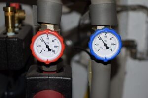 Zwei analoge Thermometer an Heizungsrohren zeigen unterschiedliche Temperaturen