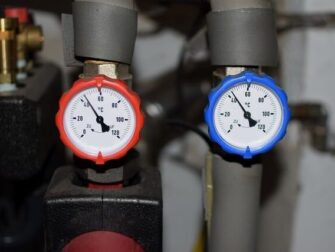 Zwei analoge Thermometer an Heizungsrohren zeigen unterschiedliche Temperaturen